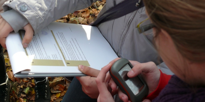 Kinder mit Navigationsgerät und Fragebogen beim Geocaching